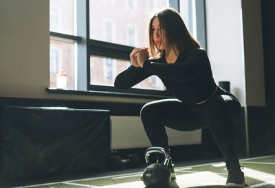 Young woman training her muscles with kettlebell in the fitness club gym