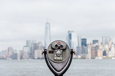 Close-up of coin-operated binoculars against cityscape