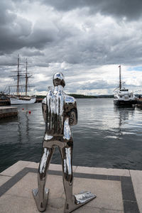 Rear view of man standing by sea against sky