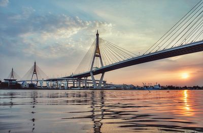 View of suspension bridge over river against cloudy sky