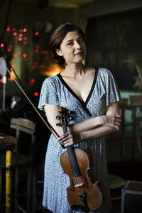 Young woman with arms raised standing at music concert