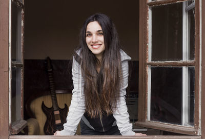 Portrait of smiling woman standing against wall