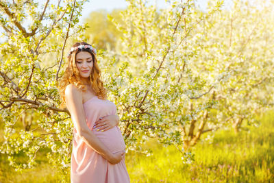 Portrait of smiling young woman standing against yellow flowering plants