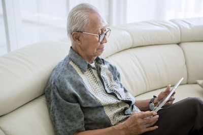 Man using digital tablet while sitting on sofa at home
