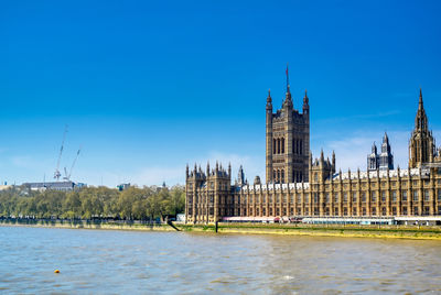 View of river and buildings against blue sky