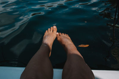 Low section of woman relaxing on pier against lake