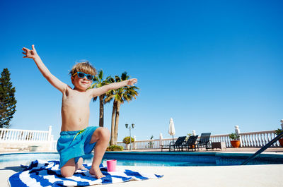 Low section of woman jumping against clear blue sky