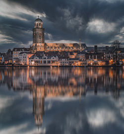 Reflection of illuminated buildings in lake against sky