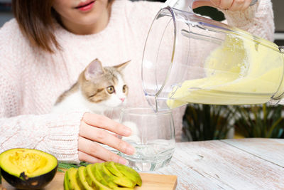 Healthy eat and lifestyle with woman making avocado smoothie and play with her cat