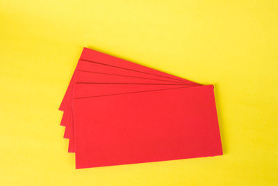 Close-up of multi colored paper against yellow wall