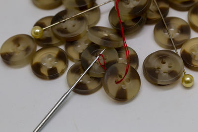 Close-up of buttons and sewing needle over white background