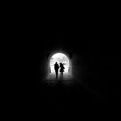 Rear view of silhouette people walking in tunnel