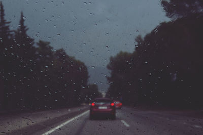 Cars on road against cloudy sky