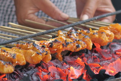 Close-up of person cooking food on fire