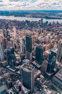 Aerial view of illuminated skyscraper buildings in city at day at high angle