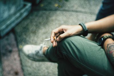 Low section of man holding cigarette