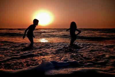 Silhouette man standing on beach against sky during sunset