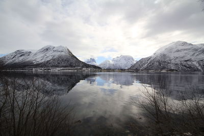 Scenic view of lake and snowcapped mountains against cloudy sky