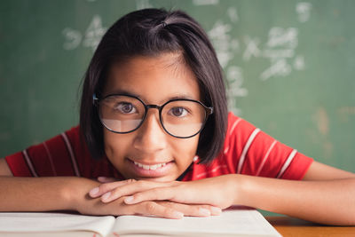 Portrait of smiling girl with book in school