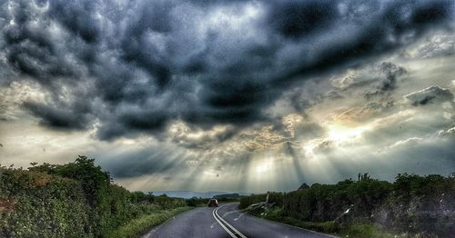 Country road against cloudy sky