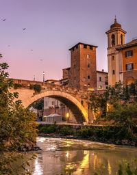 Arch bridge over river against buildings