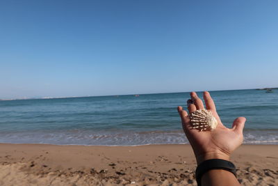 Low section of woman on beach against clear sky