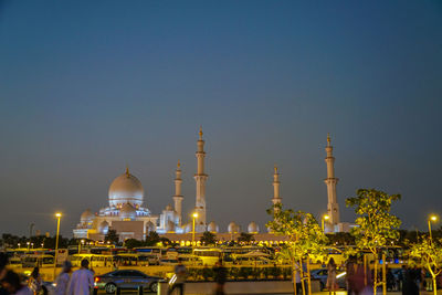 Illuminated buildings in city against clear sky