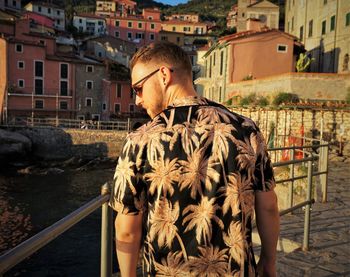 Rear view of man standing by canal in city