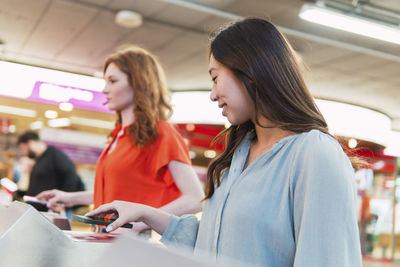 Young friends scanning qr code through smart phones at station
