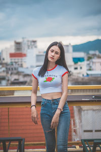 Portrait of smiling young woman standing against buildings