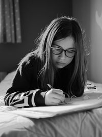 Girl writing in book on bed at home