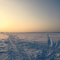 Scenic view of snow covered land against clear sky during sunset