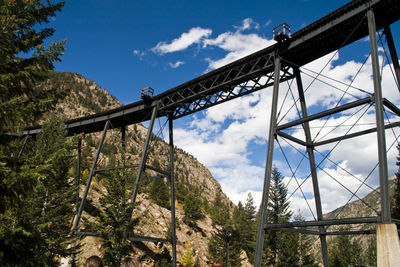 Low angle view of railway bridge at mountains against sky