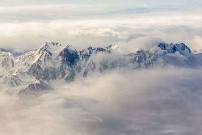 Scenic view of snow covered mountains against cloudy sky