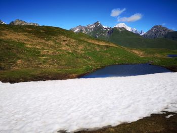 Scenic view of snowcapped mountains against blue sky