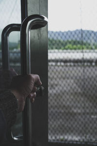 Close-up of hand holding metal fence