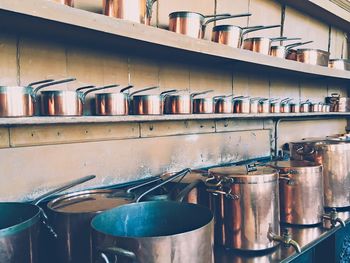 Copper utensils arranged on shelf in kitchen