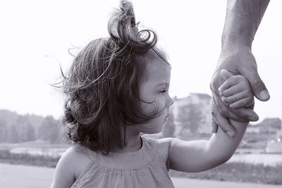 A girl holds her father's hand against the background of the city