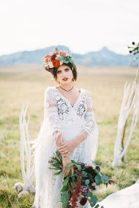 Portrait of bride standing on field against sky