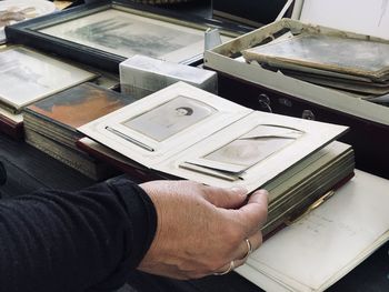 Cropped hand of man holding album on table