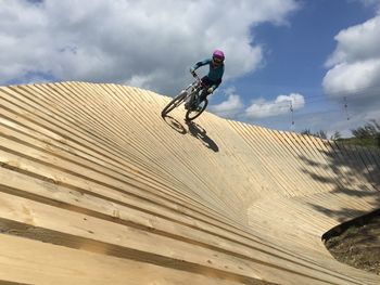 Low angle view of man riding bike against sky