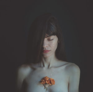 Close-up portrait of a young woman over black background