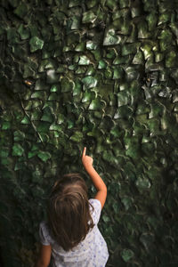 Rear view of girl touching patterned wall