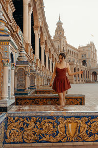 Rear view of woman standing in front of historic building