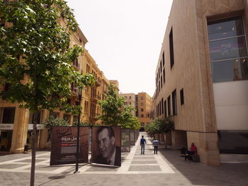 People walking on footpath amidst buildings in city