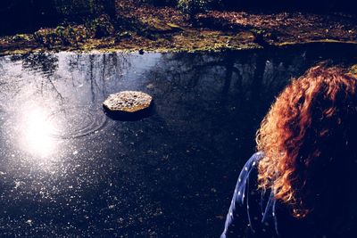 Rear view of woman standing by water