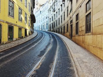 Railroad tracks by street in city against sky