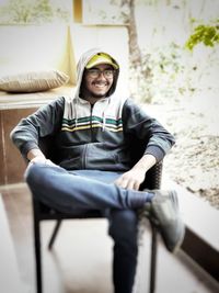 Portrait of smiling young man sitting on chair outdoors