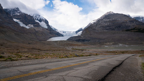 Road amidst snowcapped mountains against sky