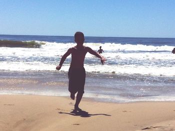 Full length of boy standing on beach against clear sky